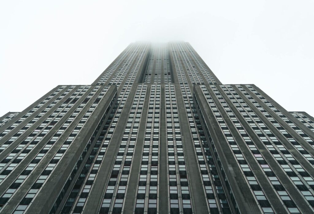Low-angle view of a towering skyscraper disappearing into the fog.